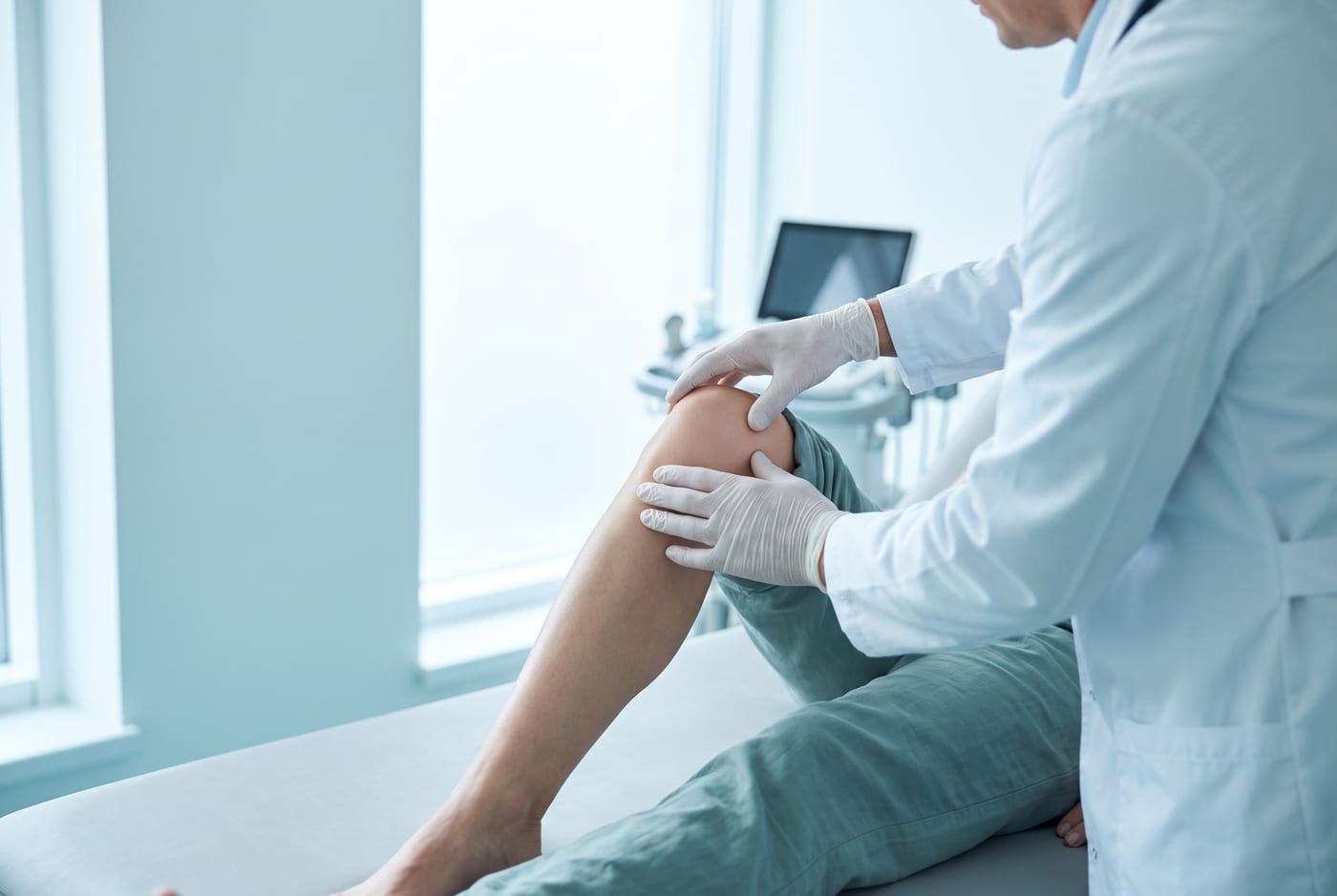 Arzt untersucht konzentriert das Knie eines Patienten in einer modernen Praxis